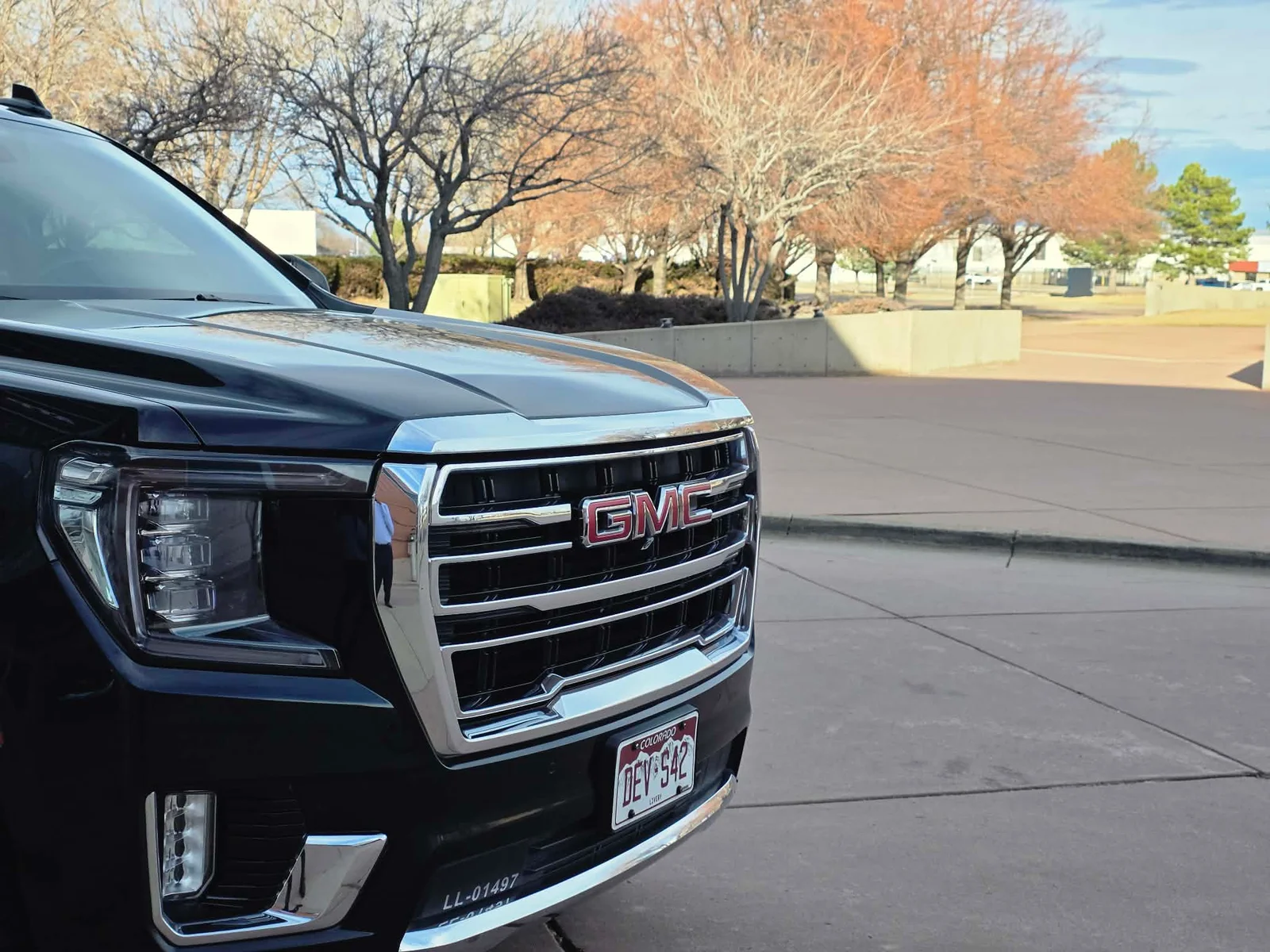 Front grille of a black GMC Yukon with Colorado plates outside a Denver-area terminal