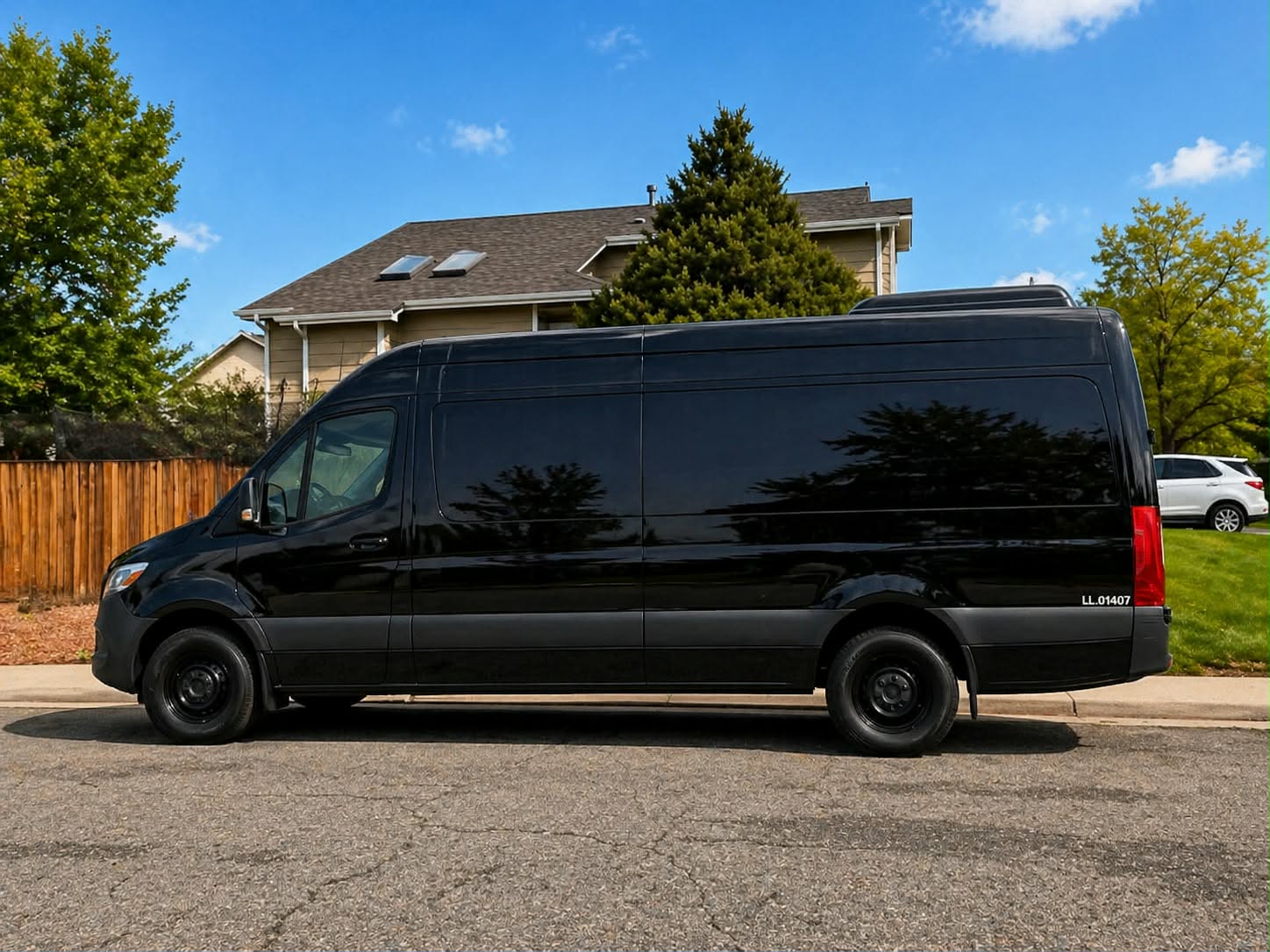 Black Mercedes-Benz Sprinter van in profile on a sunny Denver street