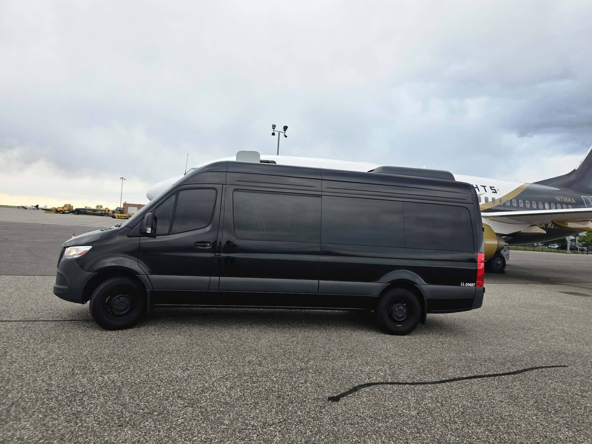 Black Mercedes-Benz Sprinter van beside a private jet on a Colorado FBO tarmac
